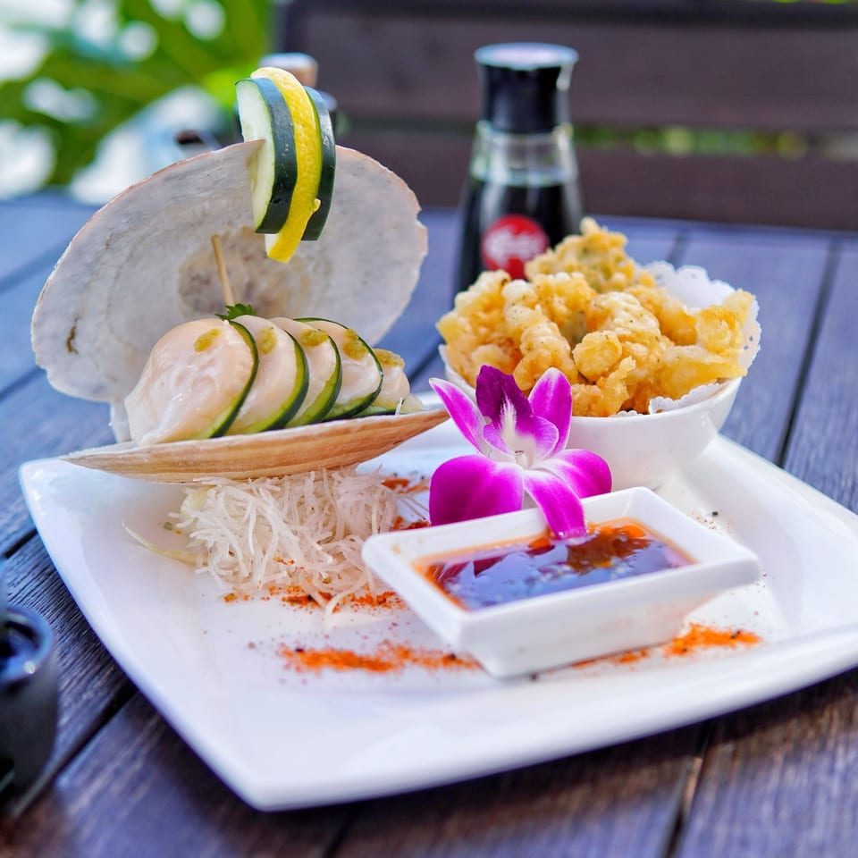 Higo Sushi and Peruvian dish with scallops in a shell, fried tempura, and dipping sauce.