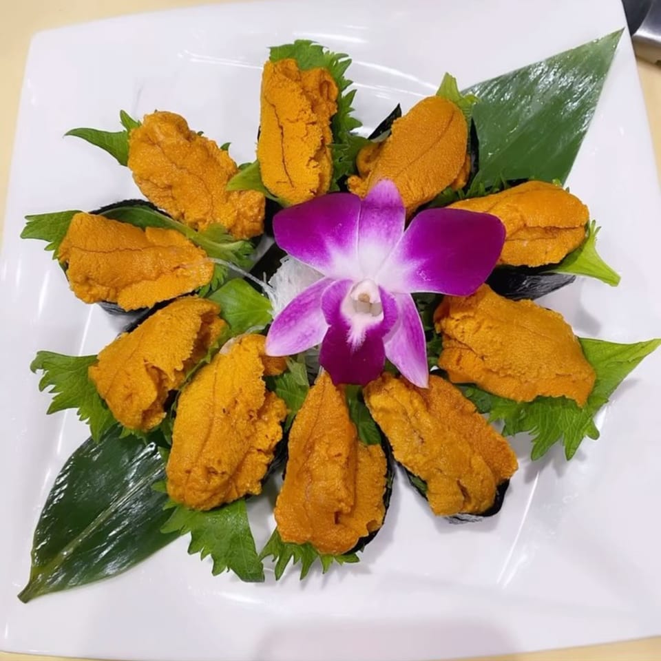 Higo Sushi's uni sushi platter, garnished with green leaves and a purple orchid.